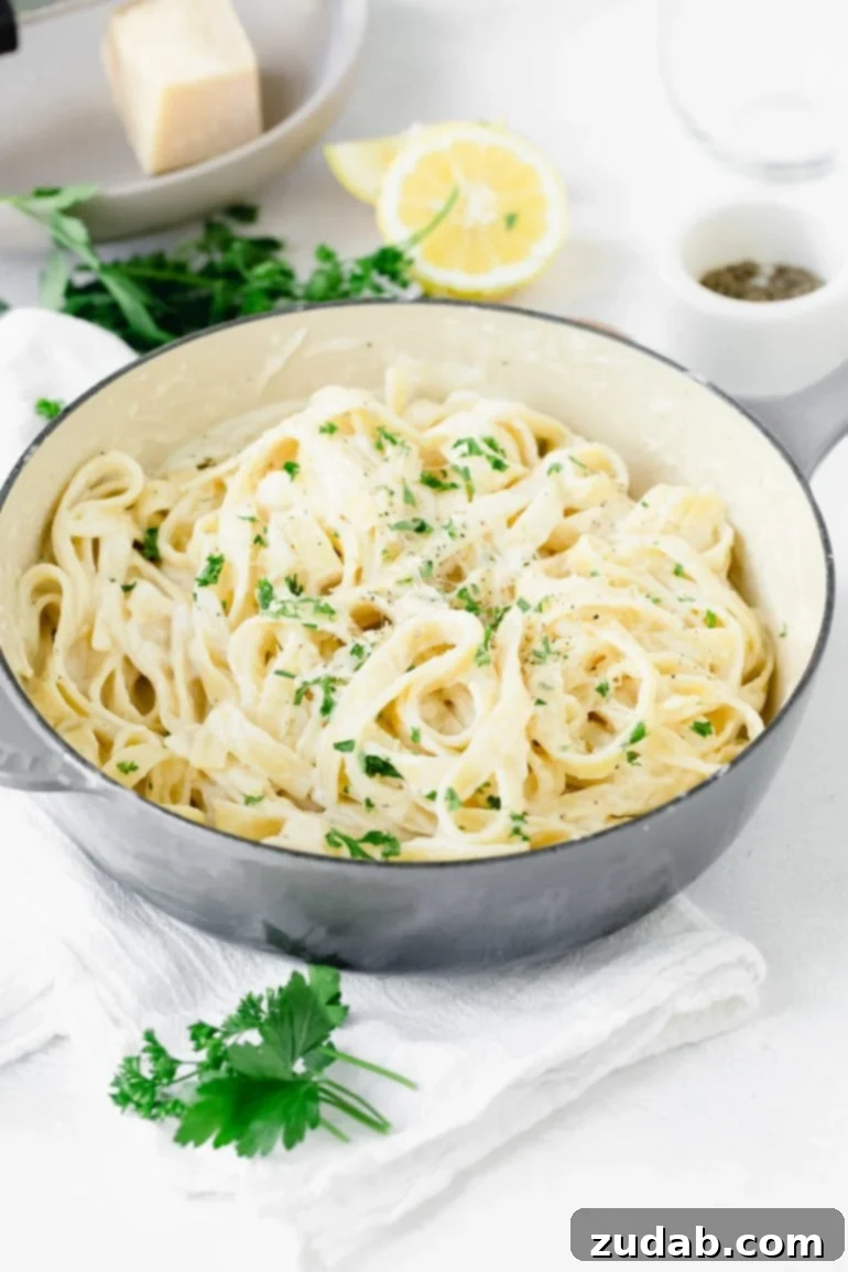 Weekly Meal Plan - September 18-24 9 A generous bowl of perfectly cooked fettuccine alfredo, generously coated in a rich, creamy white sauce, sprinkled with fresh green parsley. Alongside the bowl, there are vibrant lemon wedges and more fresh parsley for garnish.