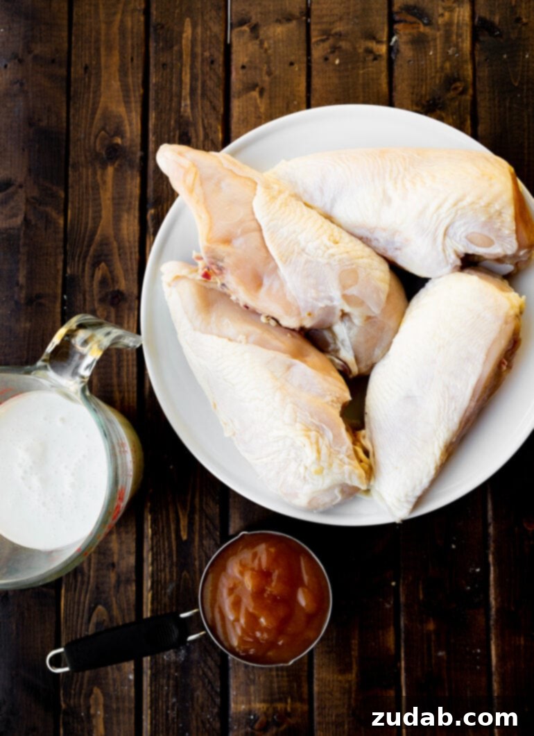 Sun-Drenched Peach Chicken 4 A white plate holds raw chicken breasts, accompanied by a measuring cup of peach preserves and a glass measuring cup of buttermilk, showcasing the marinade ingredients.