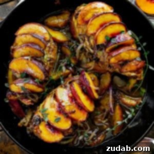 a photo of a large cast iron skillet with three chicken breasts in it each covered in sliced peaches