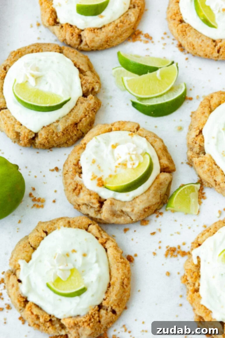 Crumbl-Inspired Zesty Key Lime Pie Cookies 4 A photo of several key lime pie cookies with lime wedges sprinkled around the cookies.