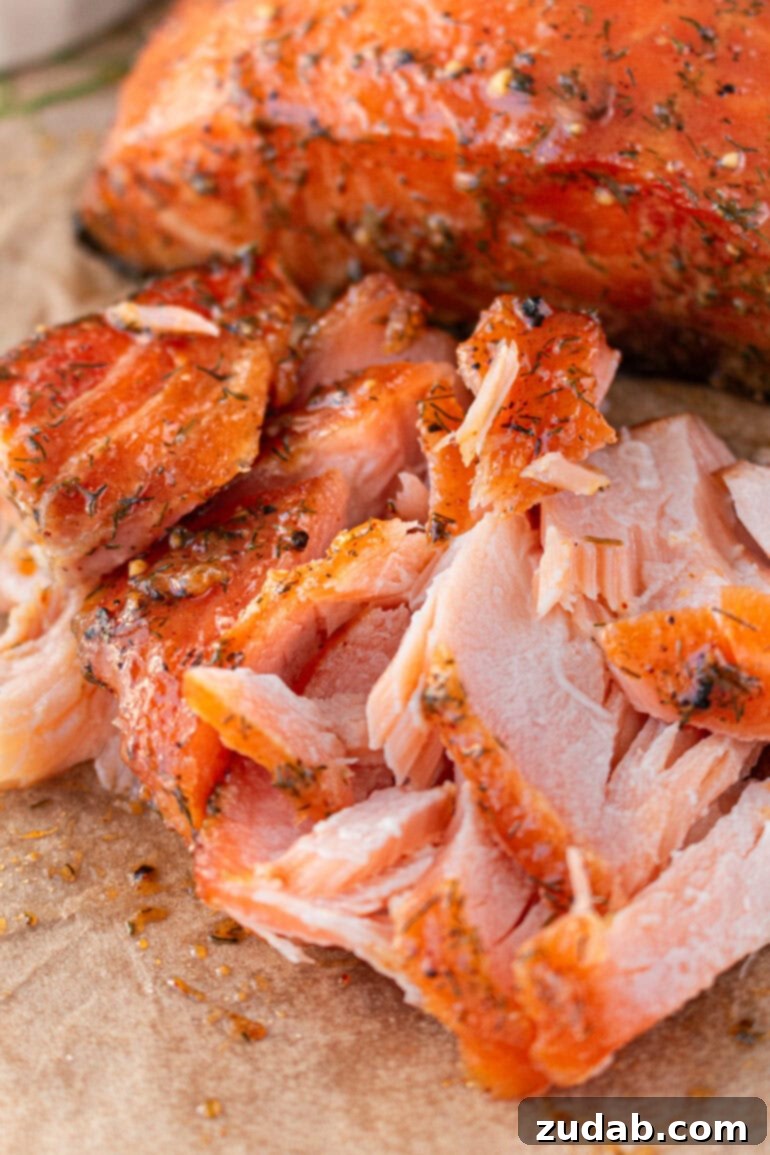Perfect Smoked Salmon Recipe 12 a photo of a smoked salmon fillet, flaked apart to show its tender interior, sitting in front of a whole smoked salmon fillet