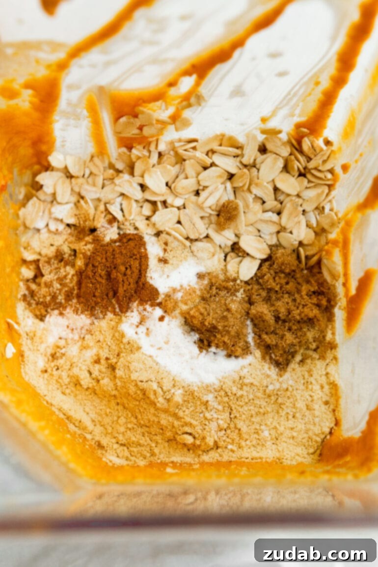 Wholesome Pumpkin Oatmeal Mug Cake 6 A blender filled with all the raw ingredients for pumpkin mug cake, including oats, spices, and pumpkin puree, poised for blending into a smooth batter.