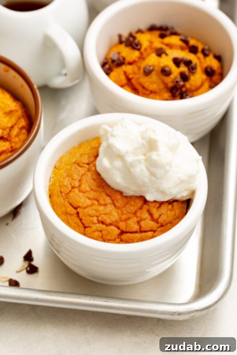 Wholesome Pumpkin Oatmeal Mug Cake 8 Several baked pumpkin mug cakes, each adorned with distinct toppings like chocolate chips and whipped cream, showcasing delightful variations.