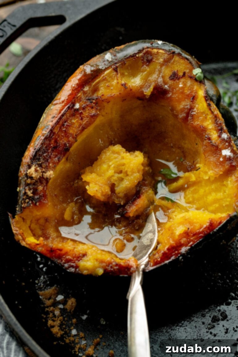 Brown Sugar Glazed Acorn Squash 2 A photo taken over the top of a halved acorn squash that has been roasted and topped with brown sugar and butter, showing golden caramelized edges.