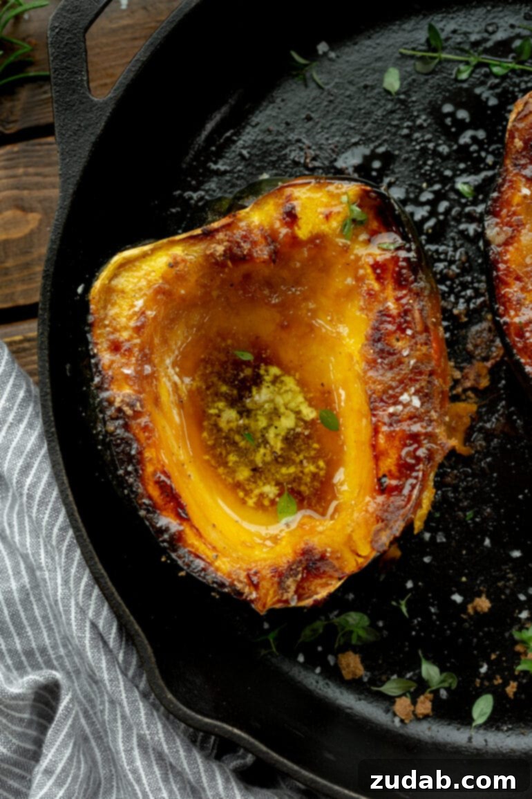 Brown Sugar Glazed Acorn Squash 5 A photo of a halved acorn squash sitting on a cast iron skillet that has been roasted until golden and caramelized with brown sugar and butter.