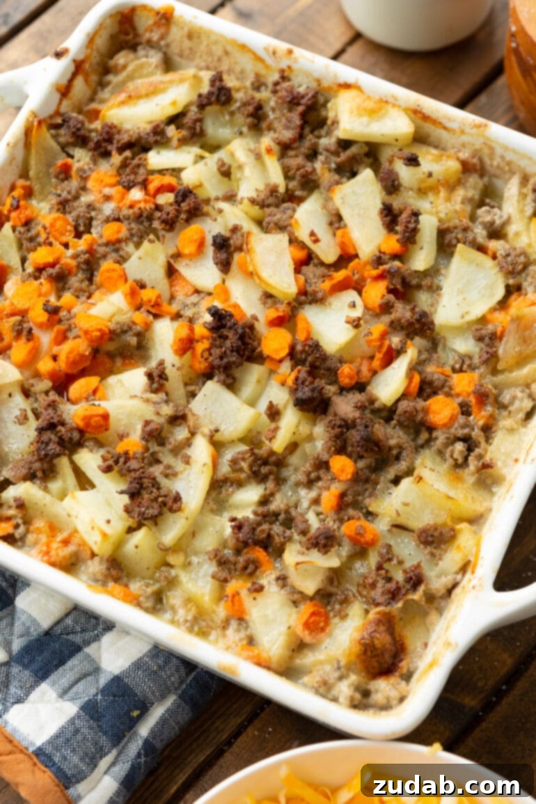 Hearty Cheesy Beef and Potato Bake 4 A square baking dish filled with a creamy mix of cooked cubed potatoes, perfectly browned ground beef, and tender sliced carrots, all coated in a rich, savory sauce.