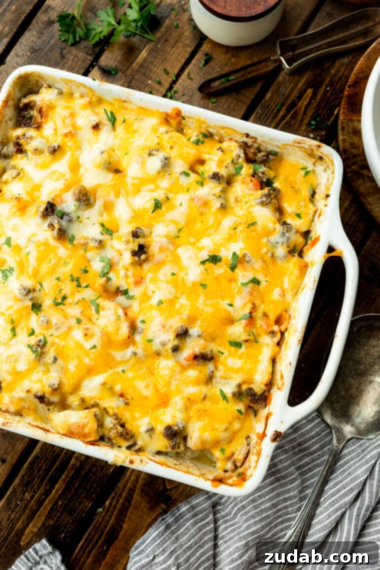 Hearty Cheesy Beef and Potato Bake 6 A square casserole dish filled with a hearty serving of cheesy ground beef and potatoes, ready to be enjoyed.