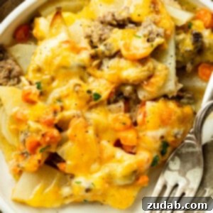 Hearty Cheesy Beef and Potato Bake 8 A photo of a dinner plate with a serving of cheesy ground beef and potato casserole on with two forks sitting next to it
