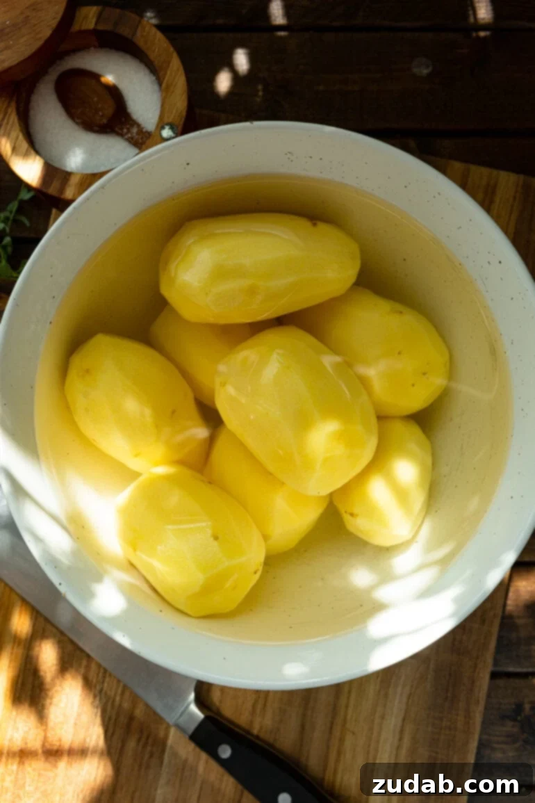 Creamy Instant Pot Mashed Potatoes 3 a photo of a bowl full of peeled whole potatoes submerged in water.