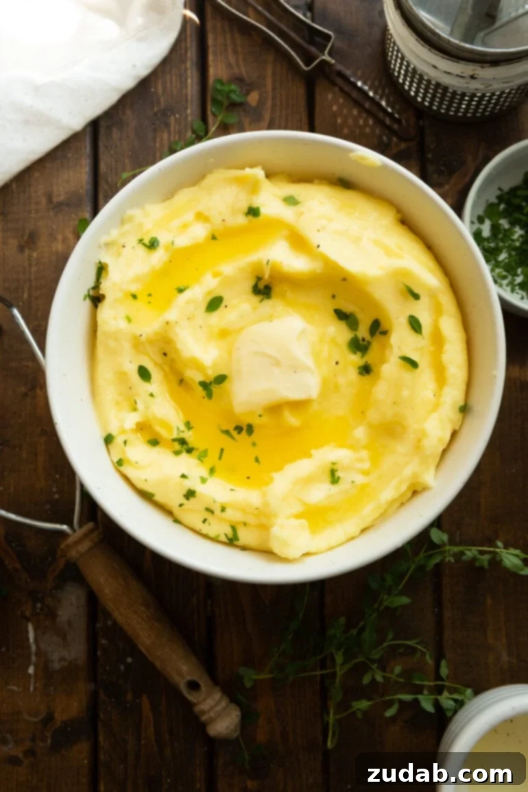 Creamy Instant Pot Mashed Potatoes 6 a photo of a large serving bowl full of creamy mashed potatoes topped with a pat of melting butter and fresh herbs