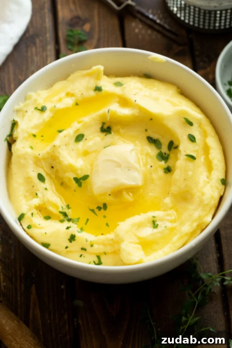 Creamy Instant Pot Mashed Potatoes 9 a photo of a bowl full of buttery mashed potatoes topped with fresh herbs and melting butter