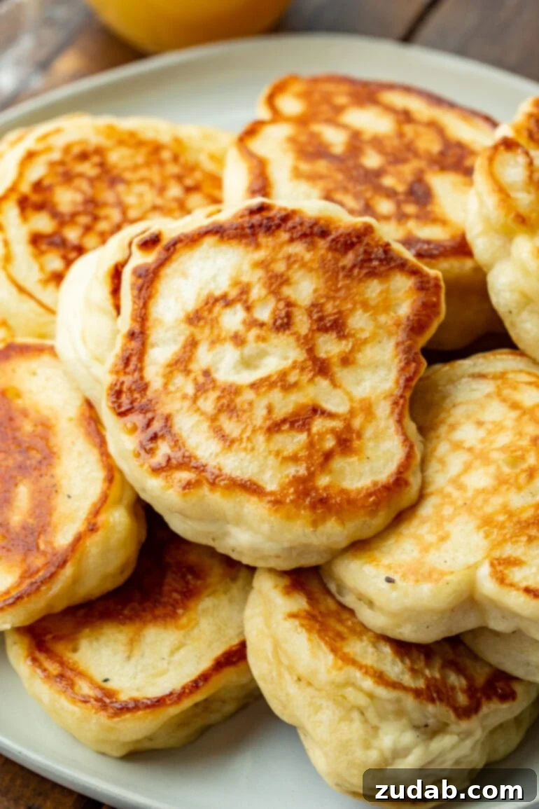 Cloud-Like Fluffy Ukrainian Oladi Pancakes 4 a photo of several golden crispy oladi pancakes piled on each other on a serving plate