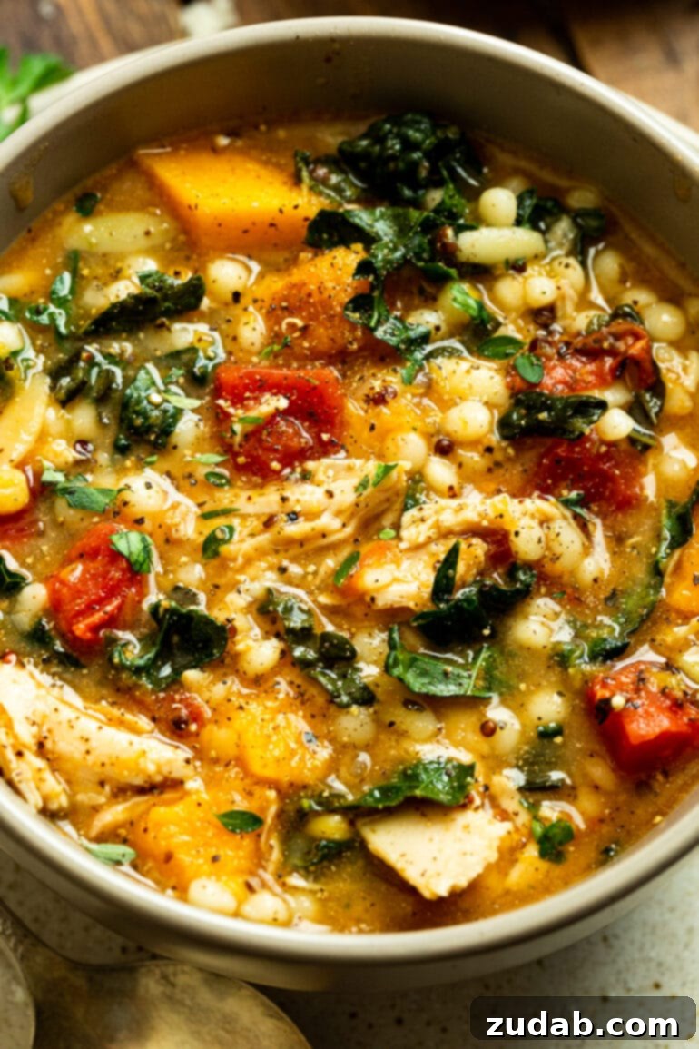A vibrant bowl of Fall Chicken Stew brimming with quinoa, tender chunks of butternut squash, succulent chicken, and fresh kale, ready to be enjoyed on a cozy evening.