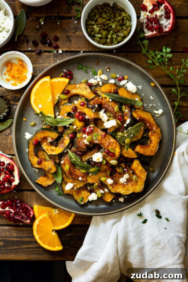 Festive Acorn Squash Delight 11 A grand serving plate piled high with vibrant holiday acorn squash, generously adorned with creamy feta, crispy fried sage leaves, and ruby-red pomegranate seeds, with fresh orange slices artfully arranged on the side for a touch of citrus.