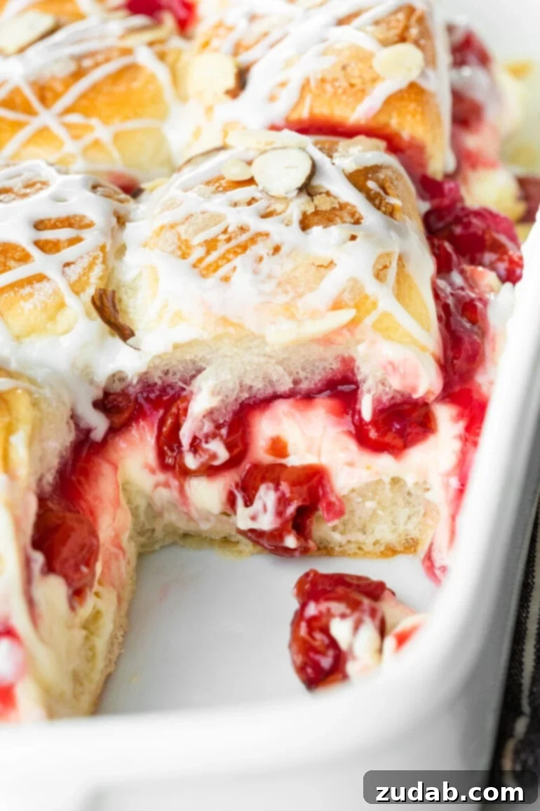Sweet Cherry Cheese Danish Sliders 4 A close-up shot of a single baked cherry cheesecake slider removed from the baking dish, revealing the luscious layers of bright cherry pie filling and creamy cheese spilling out, ready to be enjoyed.