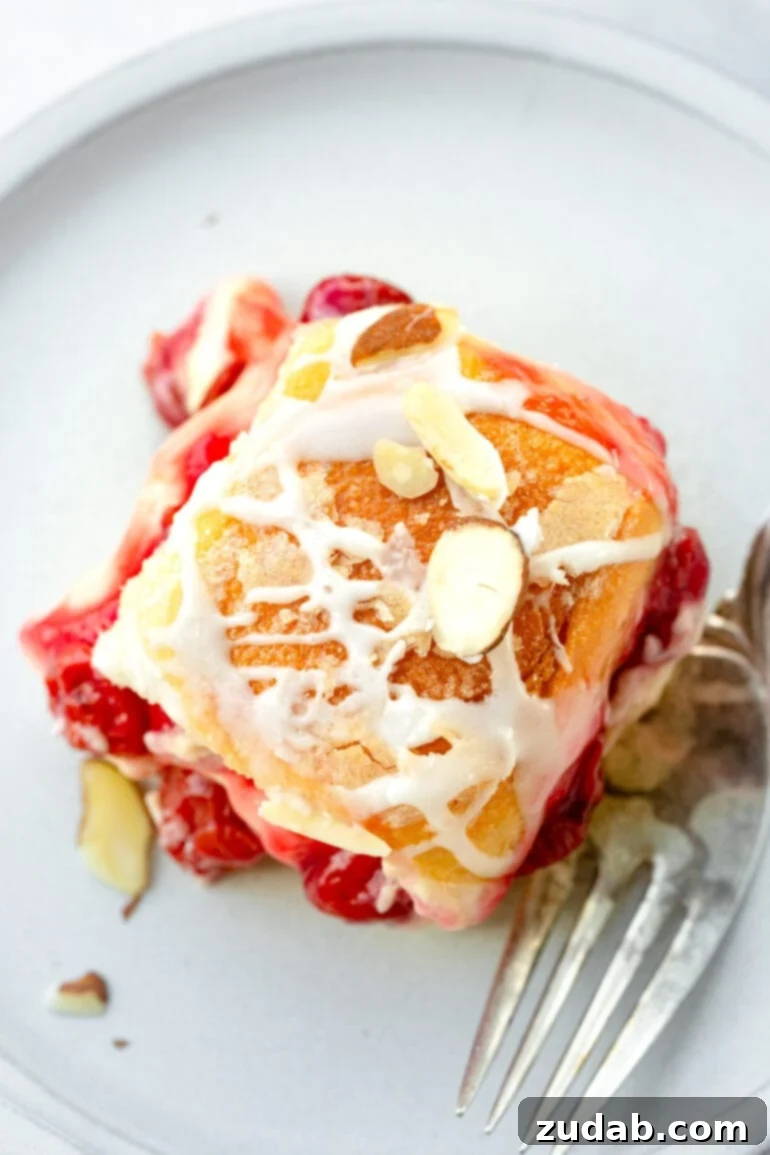 Sweet Cherry Cheese Danish Sliders 5 An overhead shot of a freshly baked, golden-brown Cherry Cheese Danish Slider, artfully topped with a luscious white glaze and delicate sliced almonds, highlighting its sweet, inviting perfection.