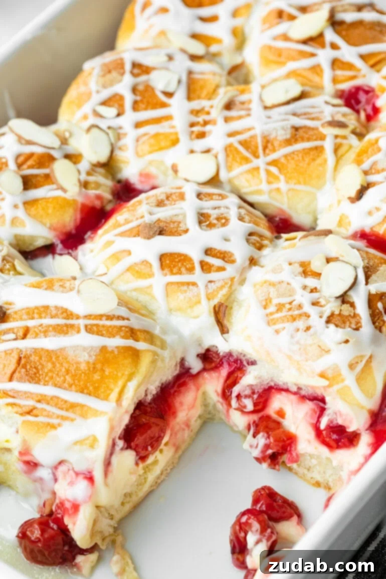 Sweet Cherry Cheese Danish Sliders 7 A close-up shot of a baking dish full of golden-baked Cherry Cheese Danish Sliders, showcasing the rich cherry and creamy cheesecake fillings. Each slider is beautifully topped with a sweet glaze and sliced almonds.