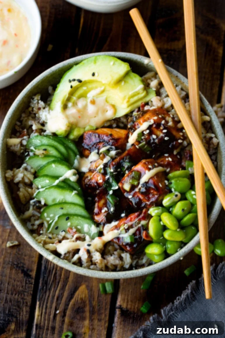 Meals for the Week of November 6-12 8 A beautifully composed bowl of fluffy rice topped with succulent teriyaki salmon chunks, bright green edamame beans, crisp cucumber slices, creamy avocado, and a sprinkle of sesame seeds, with chopsticks resting beside it.