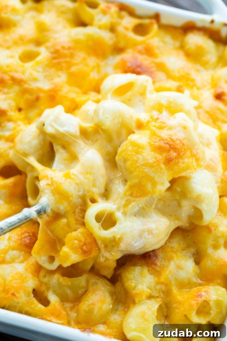 Weekly Menu Plan - Nov. 13 to 19 4 A large silver serving spoon meticulously scooping out a generous portion of incredibly cheesy, gooey Southern Macaroni and Cheese from a baking dish, highlighting its rich texture.