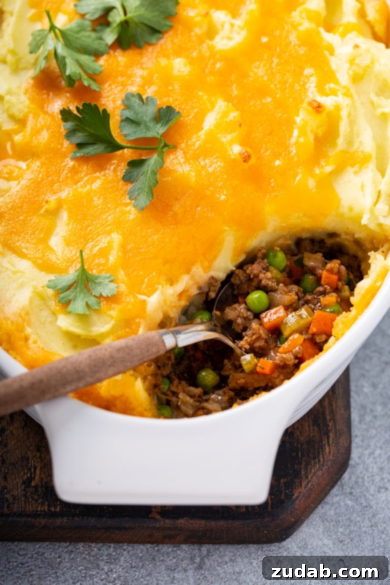 Savor the Week Meal Plan Dec 4-10 6 A rustic casserole dish filled with bubbling Shepherd's Pie, a generous spoonful removed to reveal layers of savory ground meat, vibrant carrots, and tender peas beneath a golden mashed potato topping, garnished with fresh parsley.