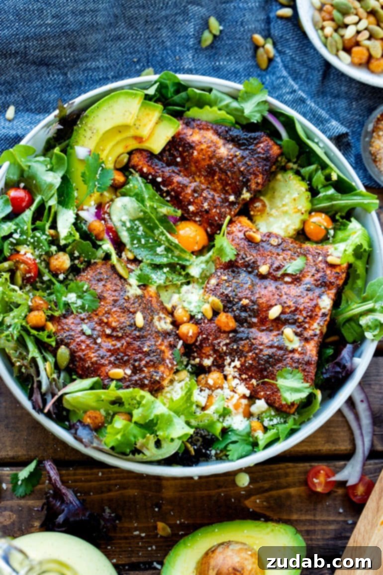 Weekly Menu Plan December 11-17 8 A vibrant serving bowl showcasing a bright arugula and cucumber salad, elegantly topped with three perfectly seasoned oven-baked salmon fillets, roasted chickpeas, and a sprinkle of toasted pine nuts and pepitas.