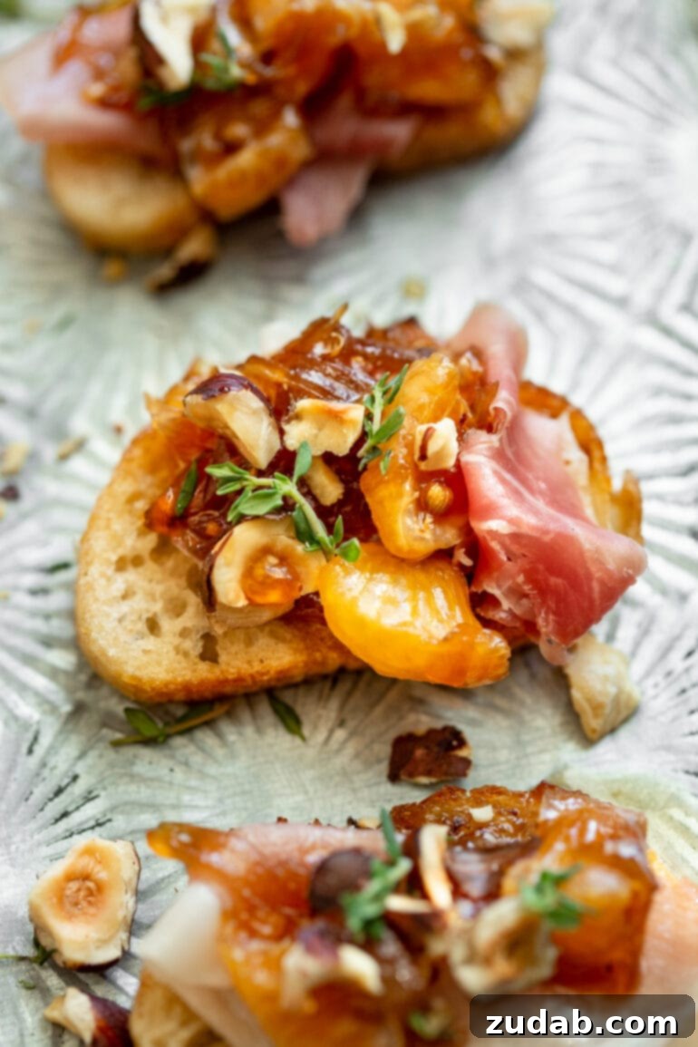 Golden Mandarin Prosciutto Bites 4 A single, perfectly arranged prosciutto and mandarin crostini, topped with toasted hazelnuts and fresh thyme.