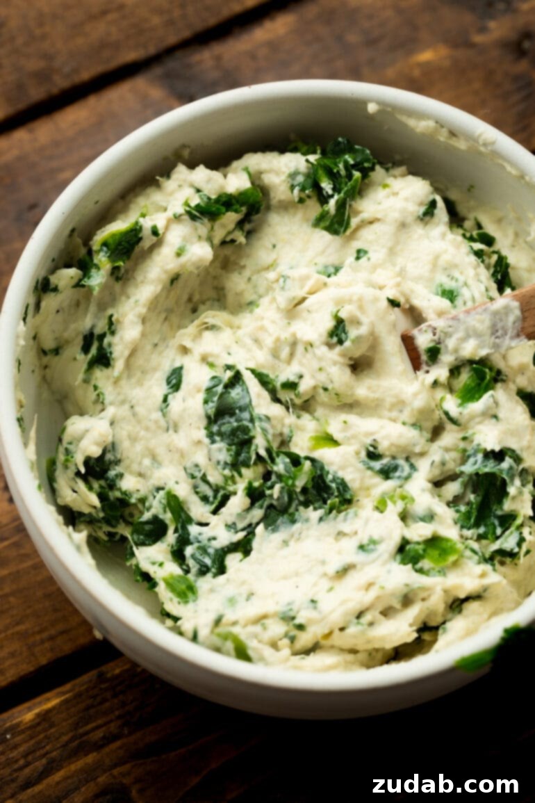 Creamy Spinach Artichoke Stuffed Salmon 4 A vibrant bowl filled with creamy spinach artichoke filling, ready to be generously stuffed into salmon fillets. The texture is smooth and inviting.