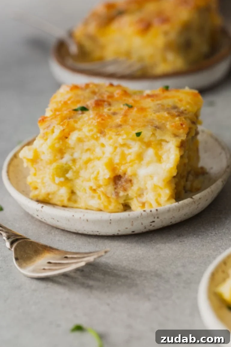 Your Holiday Week Menu December 18-24 4 A generous serving of Sausage, Monterey Jack souffle on a plate, showcasing its golden-brown top, fluffy texture, and visible pieces of savory sausage and melted cheese. A fork rests beside the plate, inviting a bite of this delicious breakfast or dinner casserole.