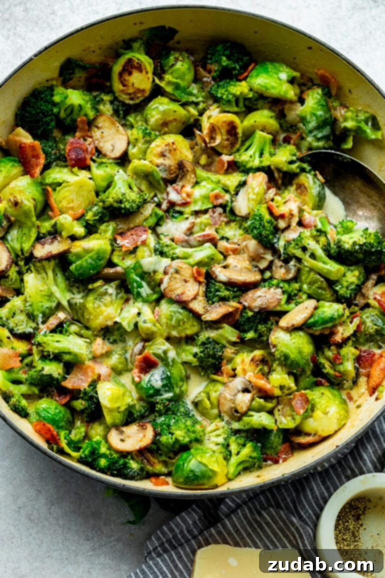 Luscious Garlic Parmesan Broccoli and Sprouts 3 A large cast-iron skillet brimming with a medley of cooked Brussels sprouts, broccoli, mushrooms, and crispy bacon, all coated in a rich, creamy sauce.