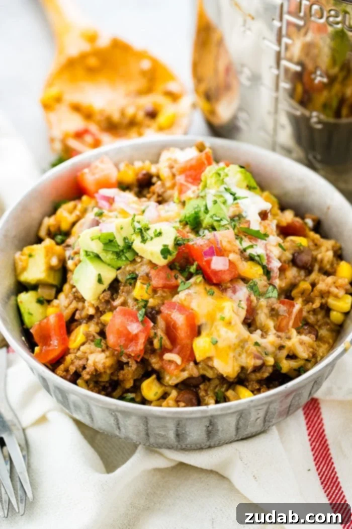 Weekly Menu Plan: January 22-28 3 A beautifully presented Instant Pot ground beef burrito bowl, garnished with vibrant chopped tomatoes, creamy avocado chunks, and fresh cilantro, showcasing a quick and easy family dinner.