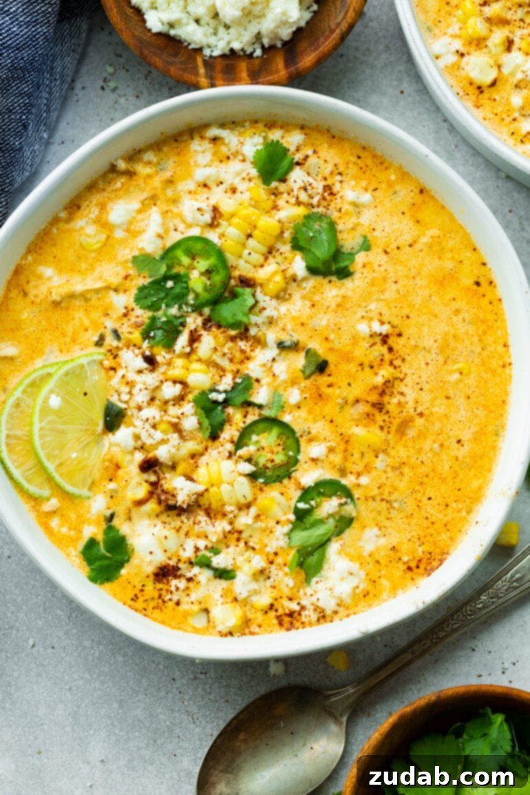 Creamy Elote Chowder 2 A large bowl of vibrant Mexican Street Corn Soup, garnished with fresh cilantro, sliced jalapeños, and lime wedges, showcasing its rich and inviting colors.