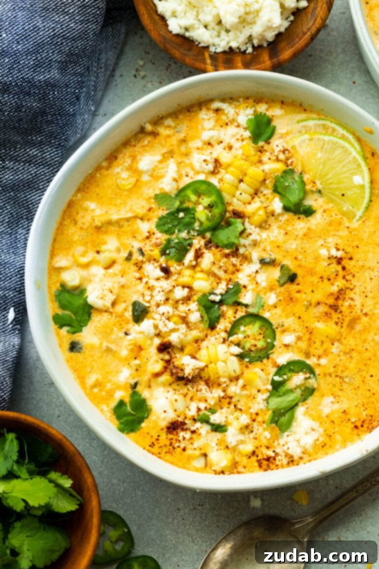 Creamy Elote Chowder 3 An overhead shot of a large white bowl filled with creamy Mexican Street Corn Soup, garnished with fresh cilantro and vibrant sliced jalapeños, ready to be enjoyed.