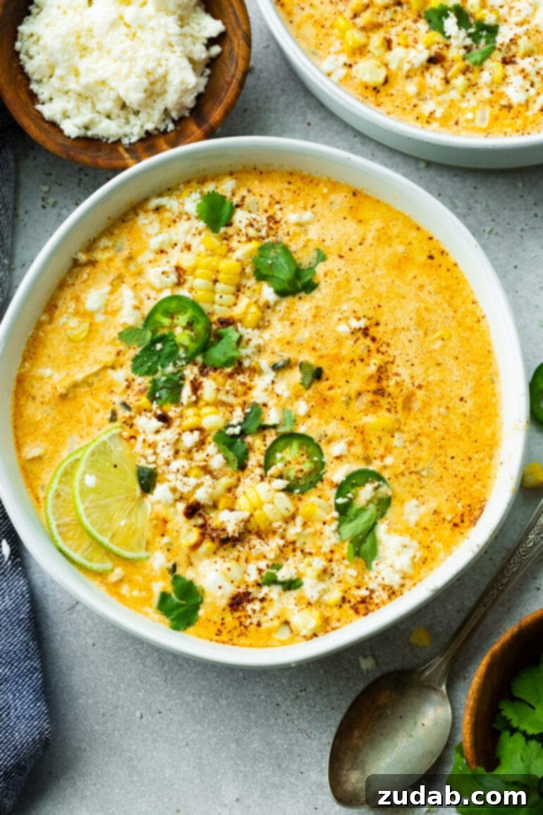 Creamy Elote Chowder 7 A generous bowl of Mexican Street Corn Soup, beautifully garnished with fresh lime wedges, chopped cilantro, vibrant jalapeño slices, and a sprinkle of crumbled cotija cheese.