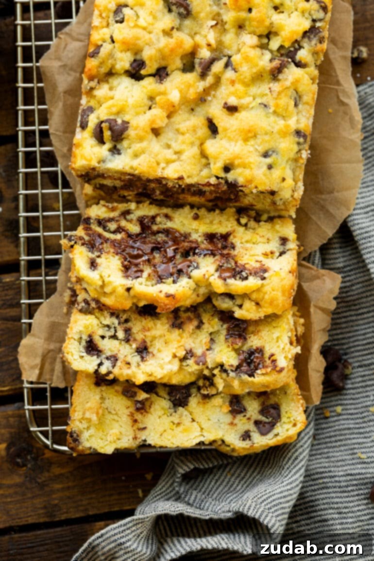 Bright Orange Chocolate Chip Scone Bread 5 A whole loaf of orange chocolate scone bread sits elegantly on a wire cooling rack, accompanied by three perfectly sliced pieces, all showcasing the beautiful golden crust and delightful chocolate chips.