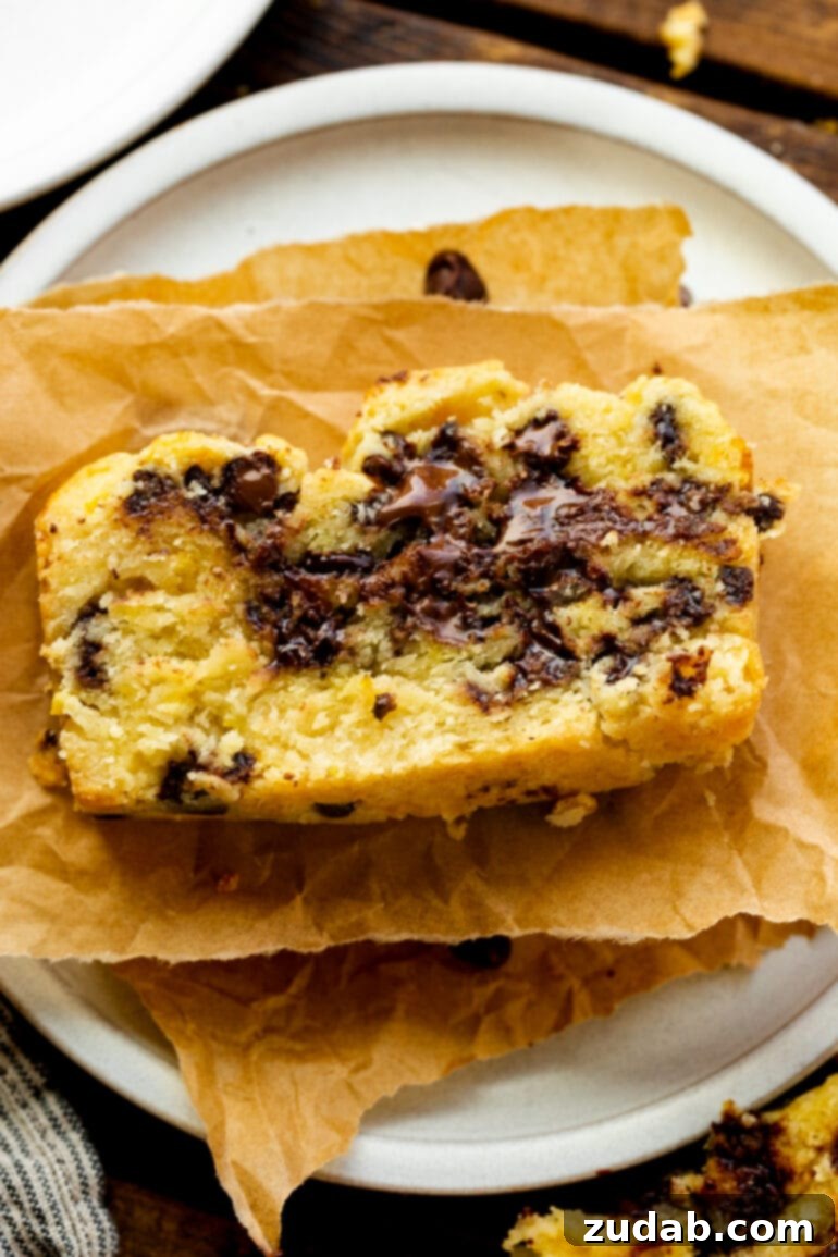 Bright Orange Chocolate Chip Scone Bread 8 A rustic, yet inviting, slice of orange scone bread, heavily laden with melted chocolate chips, artfully presented on a piece of torn parchment paper, inviting a delicious bite.