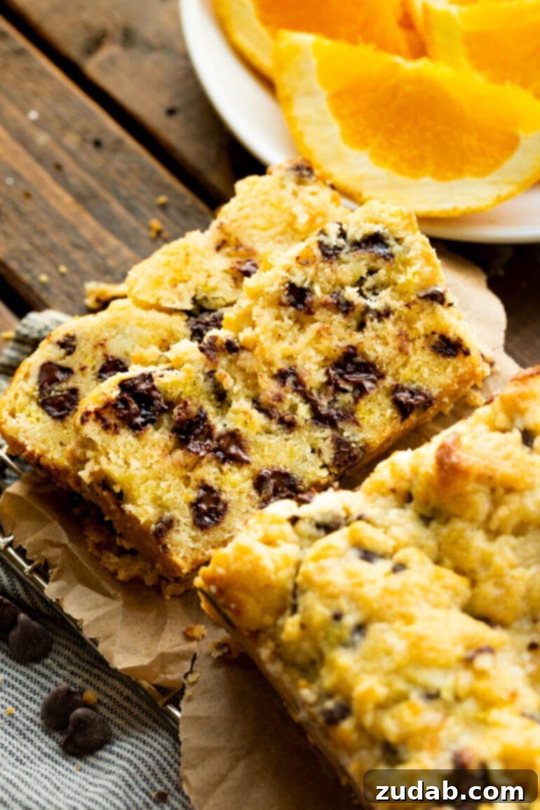 Bright Orange Chocolate Chip Scone Bread 9 A rustic photo of a loaf of orange chocolate scone bread with two slices thoughtfully removed and casually tipped against each other, highlighting the warm, inviting nature of this homemade treat.