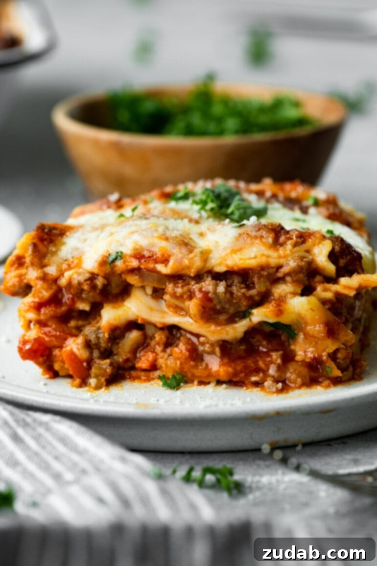 Weekly Meal Plan February 12 to 18 9 A generous serving of a truly hearty and layered meat lasagna on a pristine white plate, showcasing its rich meat sauce, creamy cheese layers, and tender pasta, topped with melted cheese and fresh parsley, embodying the ultimate Sunday comfort food.