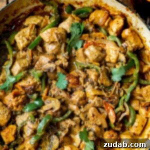 a photo of a skillet full of golden chicken chunks, sauteed bell pepper slices, onion slices, and sliced mushrooms in a creamy sauce.