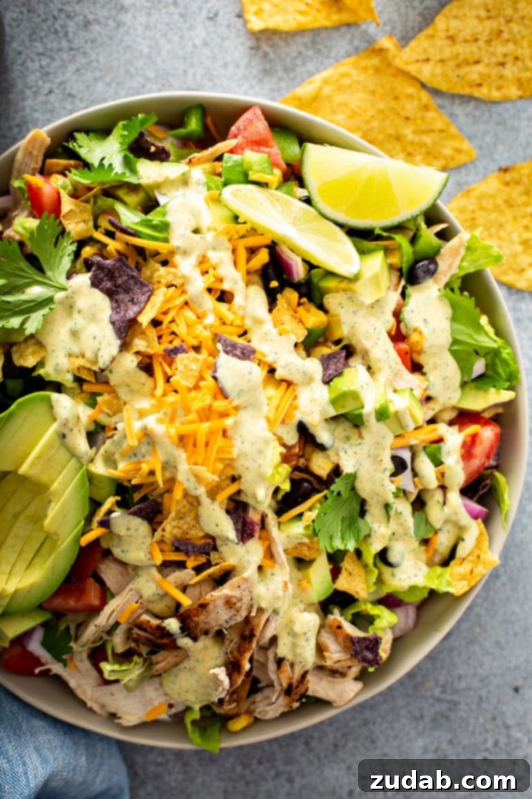 This Week's Meal Plan: February 19-25 3 A large bowl brimming with vibrant chicken taco salad, featuring shredded chicken, cheese, cilantro, black beans, corn, diced tomatoes, red onions, bell peppers, and sliced avocados. Accompanied by lime wedges, tortilla chips, and a creamy dressing.