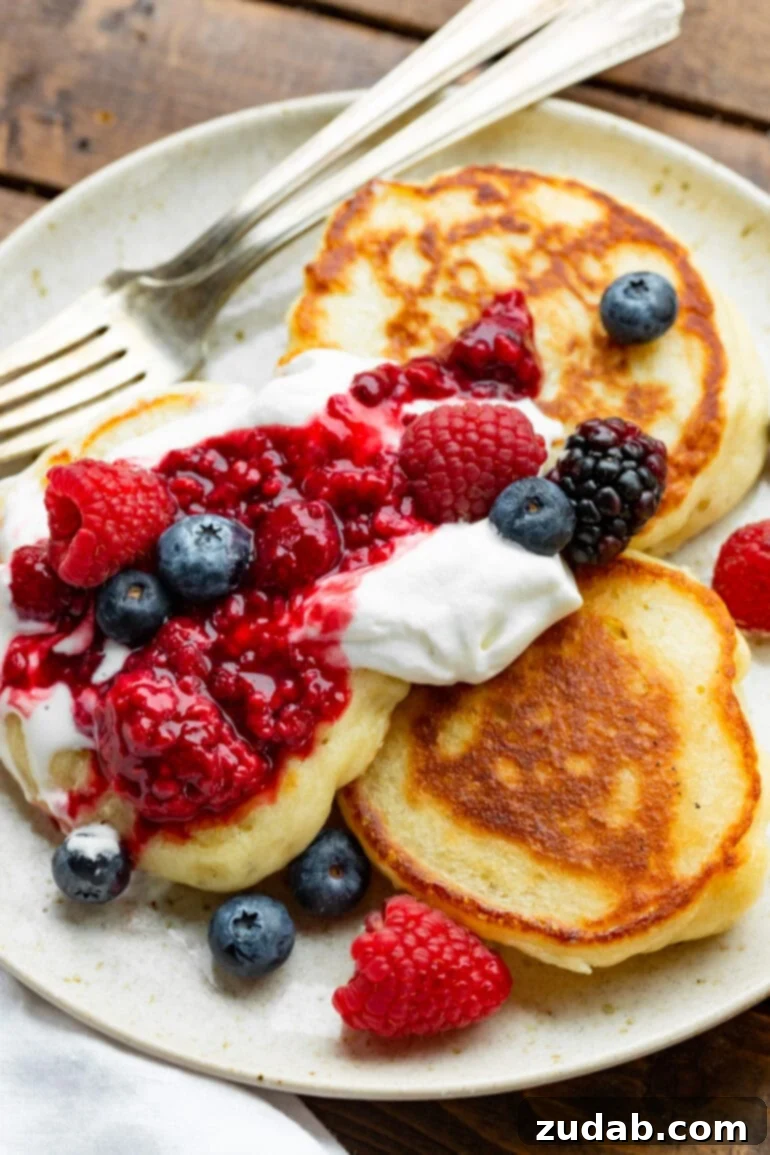 This Week's Meal Plan: February 19-25 5 A stack of golden-brown fluffy Ukrainian pancakes (oladi), garnished with fresh berries and a dusting of powdered sugar.