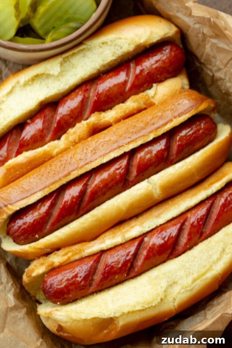 Crispy Air Fryer Hot Dogs 2 A photo of three air-fried hot dogs in buns with the tops perfectly scored and crisped, ready for toppings.