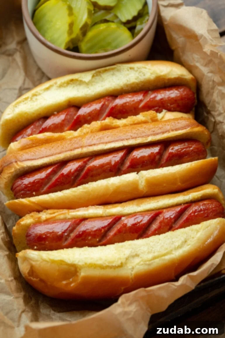 Crispy Air Fryer Hot Dogs 5 A photo showcasing three crispy air-fried sausages in brioche buns, with visible scoring on the hot dogs.