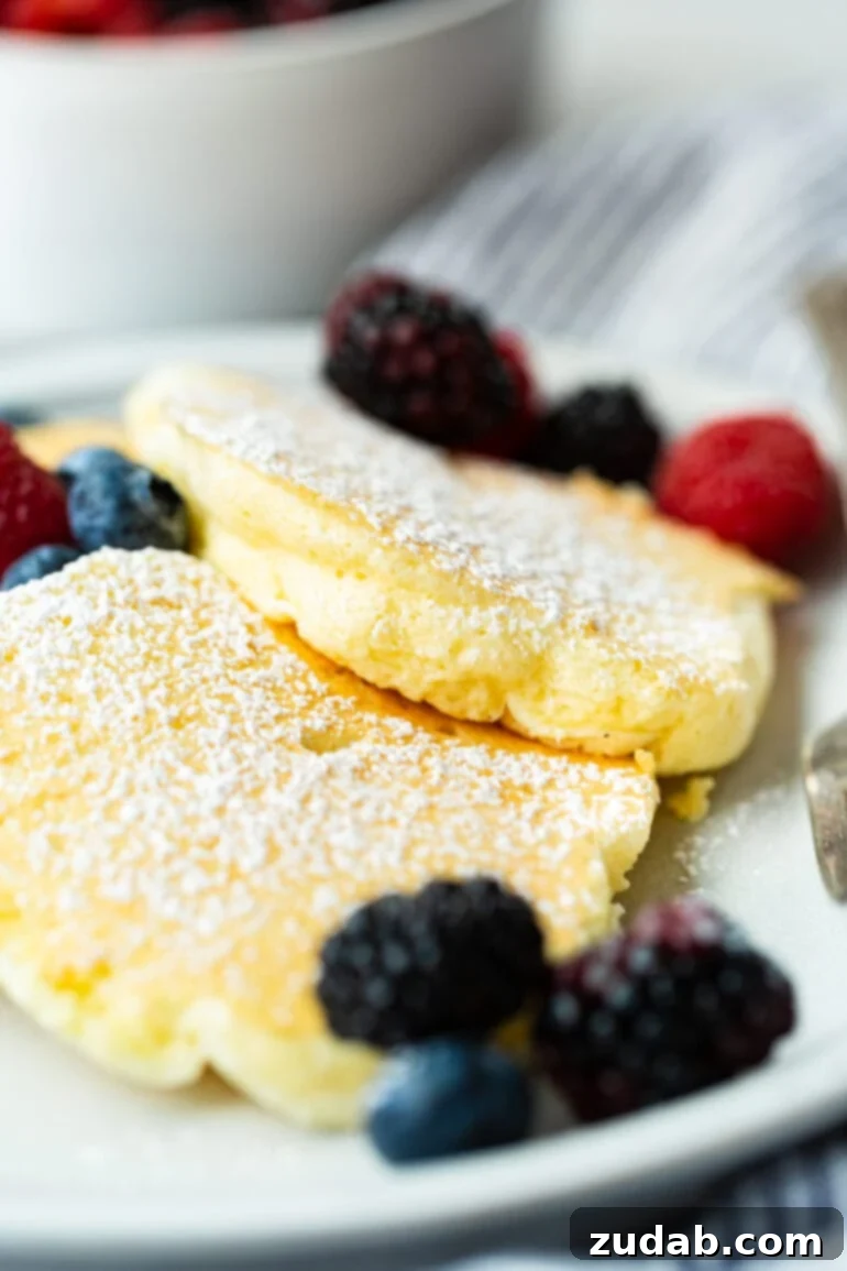 Your Weekly Meal Plan: Feb 26 - Mar 3 7 Three exquisitely fluffy, golden Japanese cloud pancakes elegantly arranged on a plate, dusted with powdered sugar and adorned with a medley of fresh mixed berries.