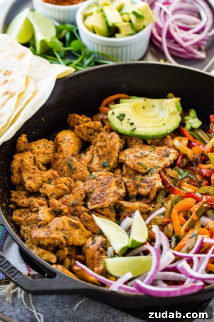 Weekly Menu Plan: Mar. 11-17 3 A photo of a cast iron skillet full of chicken fajita filling - cooked chicken, sauteed peppers and onions, lime wedges, sliced purple onion, and sliced avocados.
