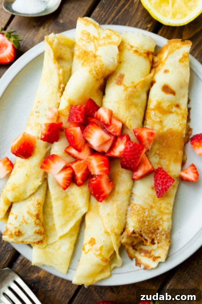 Weekly Menu Plan: Mar. 11-17 4 a photo of four swedish pancakes rolled up and sitting next to each other on a white plate topped with diced strawberries.