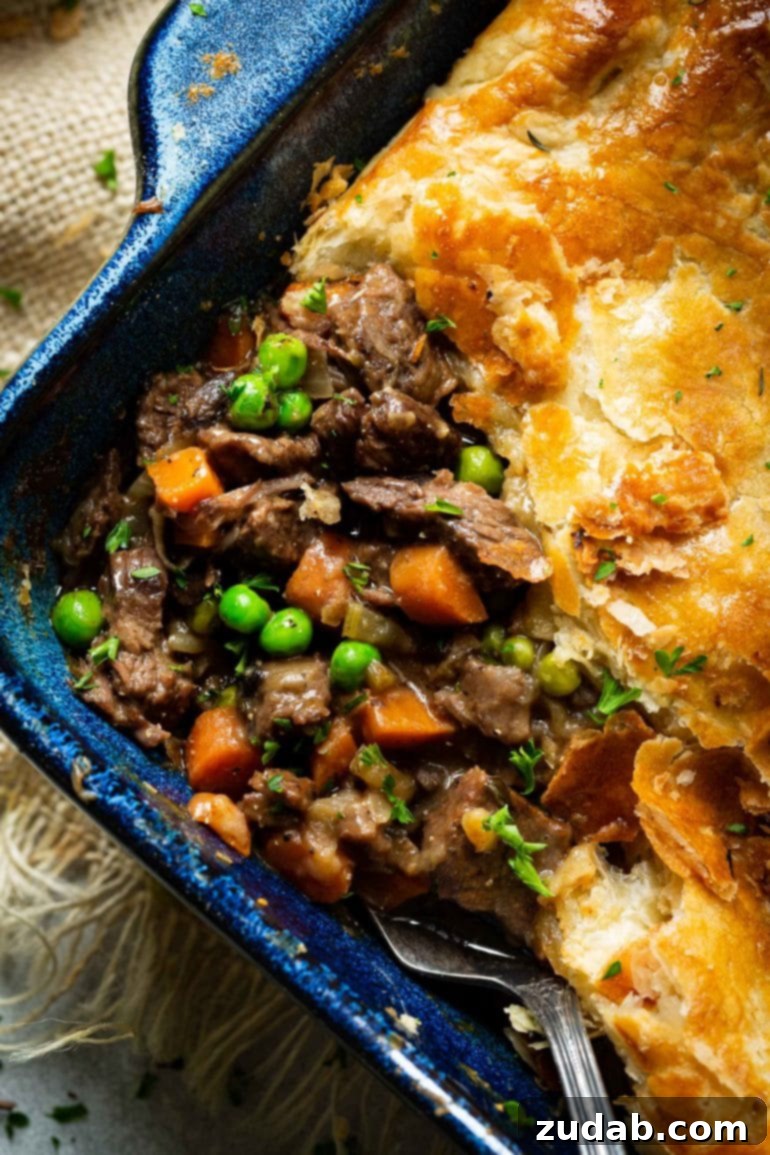 Weekly Menu Plan: Mar. 11-17 5 a photo of the corning of a baking dish full of beef pot pie with a serving removed so you can see the saucy beef filling with carrots and peas and onions and topped with golden puff pastry.