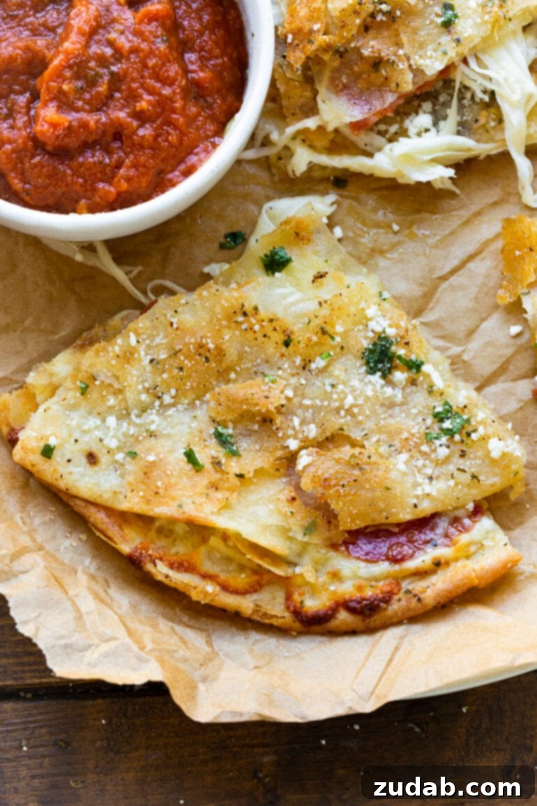 Pizza-dilla: A Cheesy Pizza Quesadilla 5 A golden and crispy slice of tortilla pizza with luscious, melty cheese emerging from its sides, beautifully topped with cotija cheese and a sheen of garlic butter, placed beside a small bowl of dipping pizza sauce.