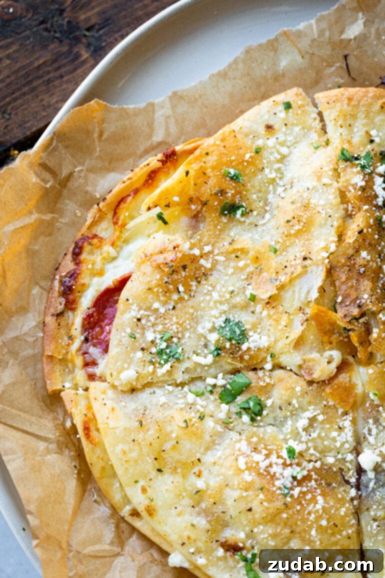 Pizza-dilla: A Cheesy Pizza Quesadilla 6 A close-up of a crispy, golden pizza quesadilla, generously topped with crumbled cotija cheese and vibrant chopped cilantro.