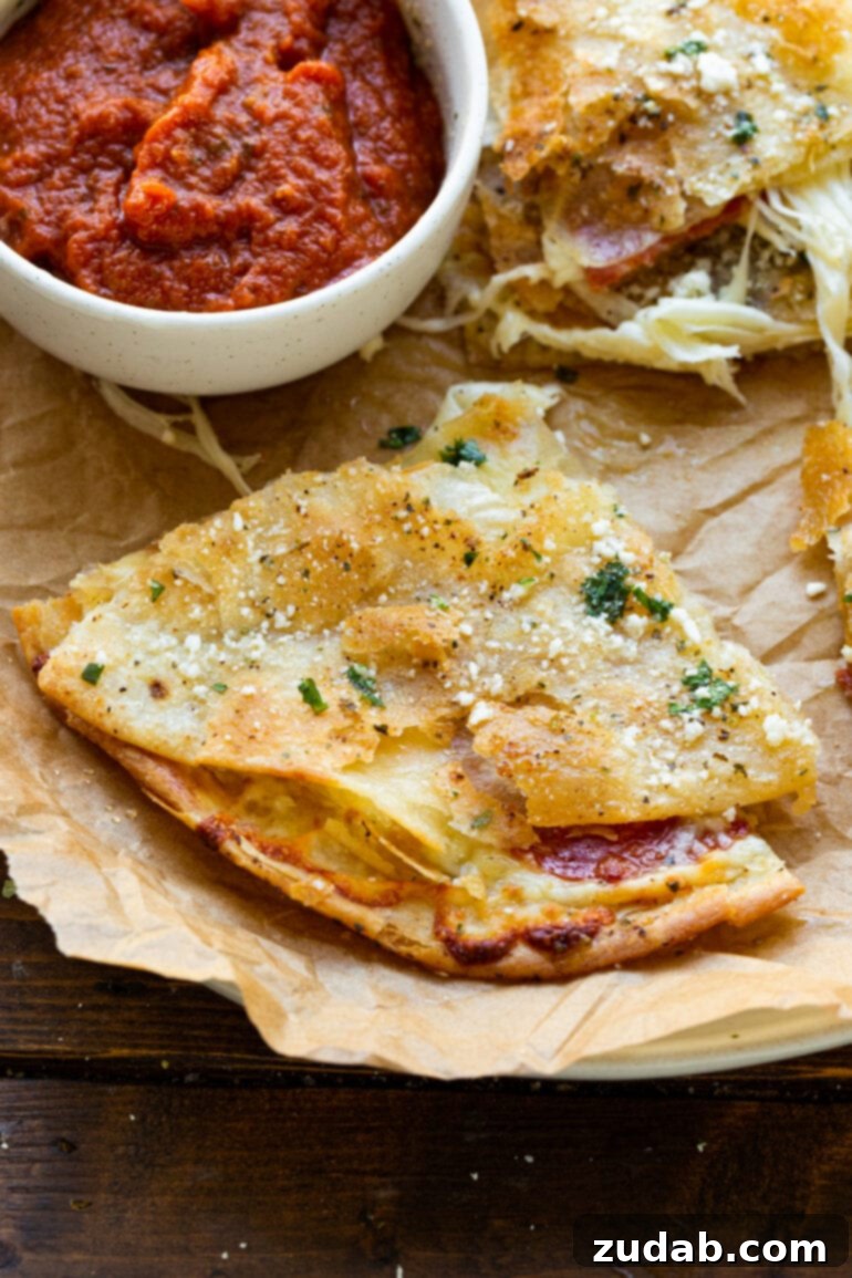 Pizza-dilla: A Cheesy Pizza Quesadilla 7 A perfectly crispy and golden quarter-slice of pizza quesadilla, placed enticingly next to a small cup of rich pizza sauce for dipping.