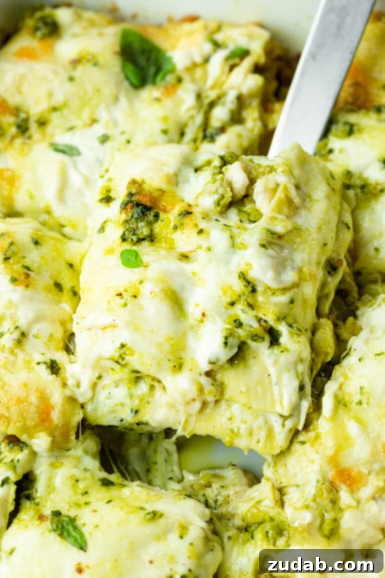 Effortless Creamy Pesto Chicken Lasagna 3 A spatula lifting a generous, creamy slice of pesto chicken lasagna from a baking dish, highlighting the rich layers.